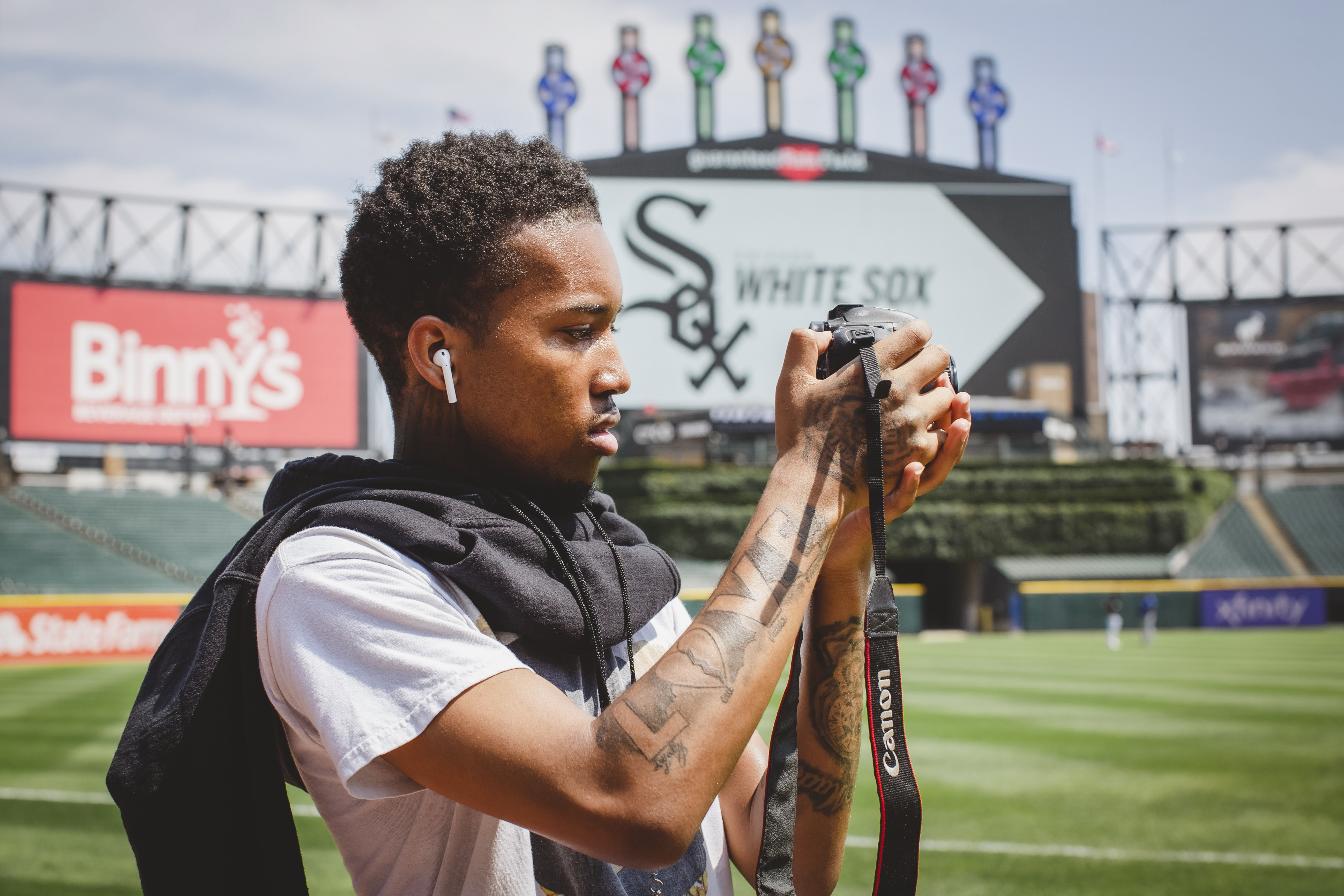Young photographer holds camera with baseball field in background